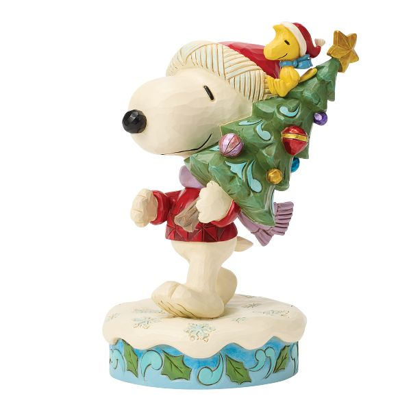 Jim Shore Peanuts Figur Snoopy trägt Weihnachtsbaum mit Woodstock handbemalt in Holzoptik auf verschneitem Sockel